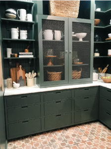 pantry with green cabinetry and terracotta floors